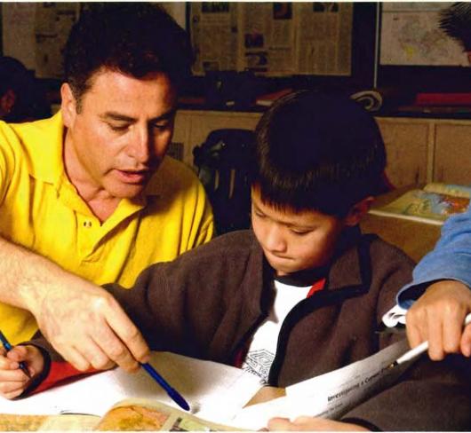 teacher showing elementary student in book