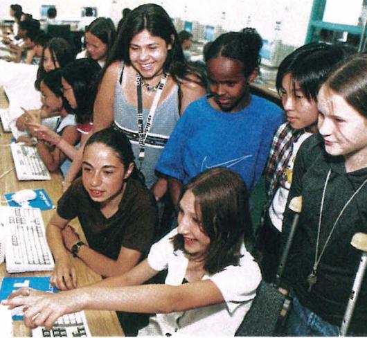 women and children in classroom using computer