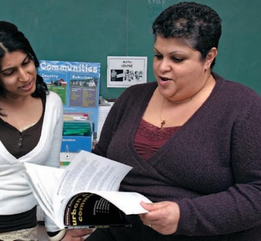 Two teachers flipping through textbook
