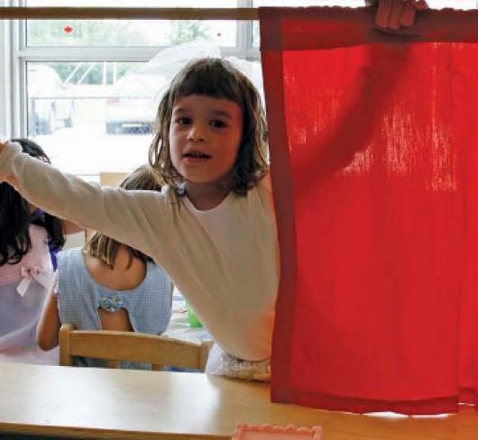 young girl opening red curtain 