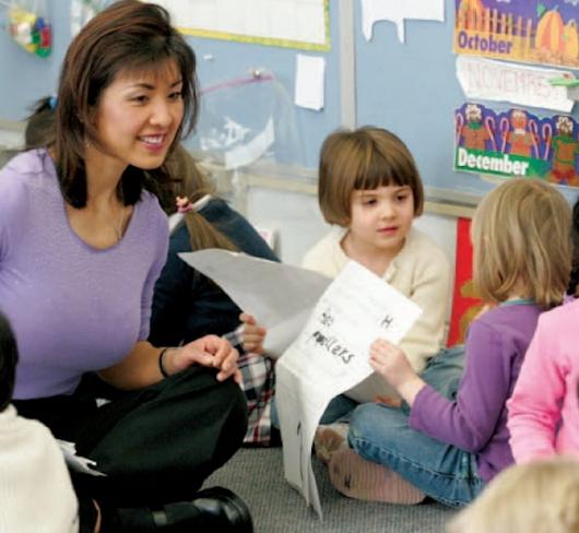Teacher interacting with kindergarten students who have books