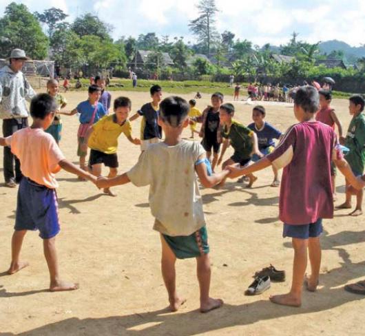 Young children holding hands in circle while two children chase one another within