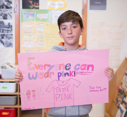 Male student holding paper that says "everyone can wear pink"