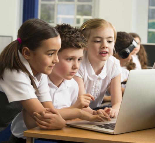 Young elementary students looking at laptop