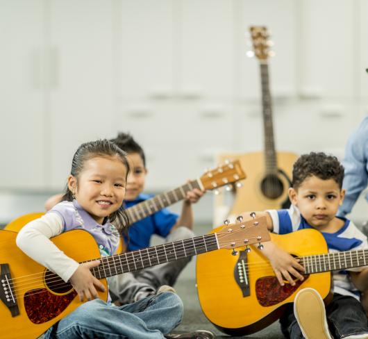 Elementary students learning music with acoustic guitars